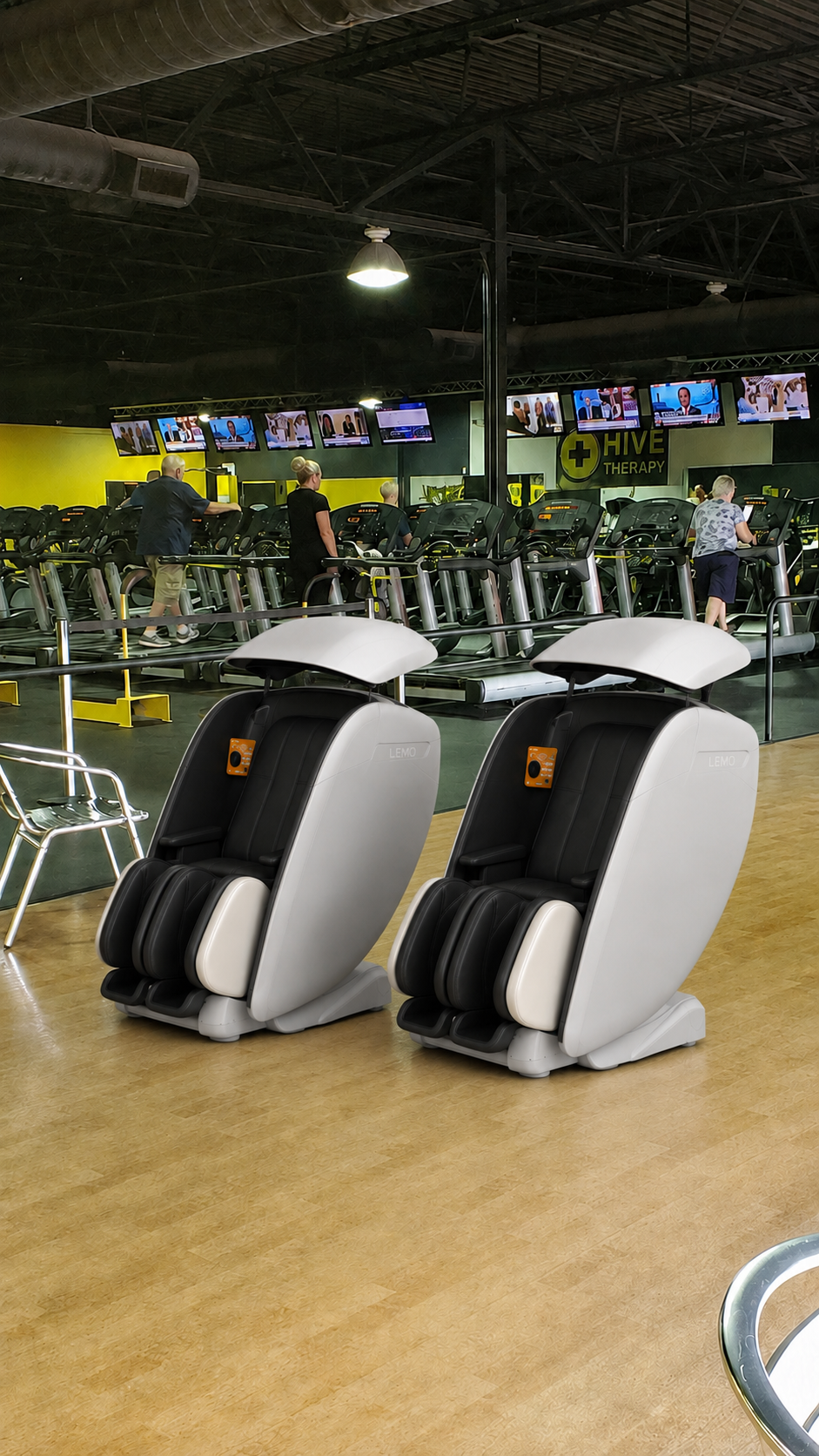 Two Lemo recovery chairs installed on the HIVE Therapy gym floor with treadmills and HIVE signage in the background